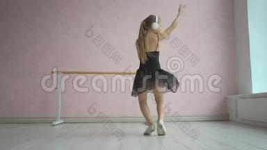 戴着耳机听智能手机音乐跳舞的快乐小女孩